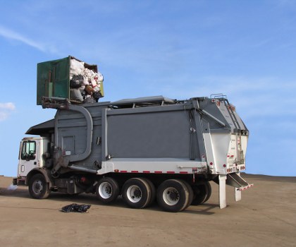 Trained waste removal staff wearing high-visibility PPE preparing a vehicle